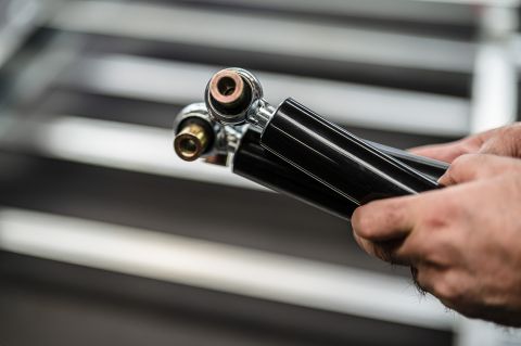 Ein Stoßdämpfer für Anhänger wird von einem Mitarbeiter geprüft und vorbereitet