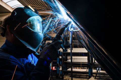 Ein Schweißer führt Schweißarbeiten an einer Anhänger-Konstruktion durch