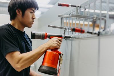 Mitarbeiter im Fahrzeug- und Anhängerbau befestigt mit Druckluftnietgerät ein Bauteil am Aufbau