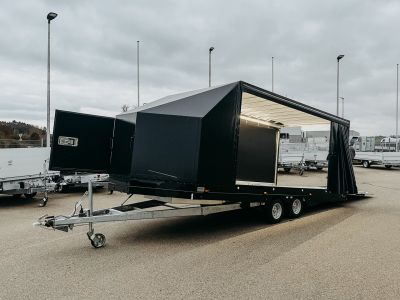 Geöffneter Fahrzeugtarnsport- und Präsentationsanhänger mit schwarzem Kofferaufbau, Innenbeleuchtung und Auffahrrampe, abgesenkt und seitlich geöffnet