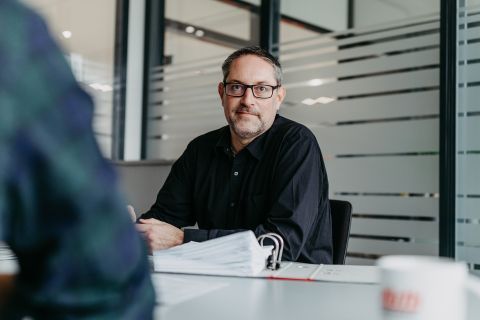 Mann bei Beratungsgespräch mit Unterlagen am Besprechungstisch