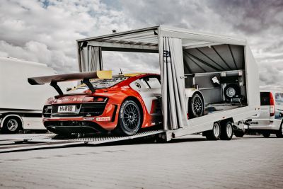 Rennwagen auf offenem Autotransport-Anhänger mit seitlich verschiebbarem Planenaufbau