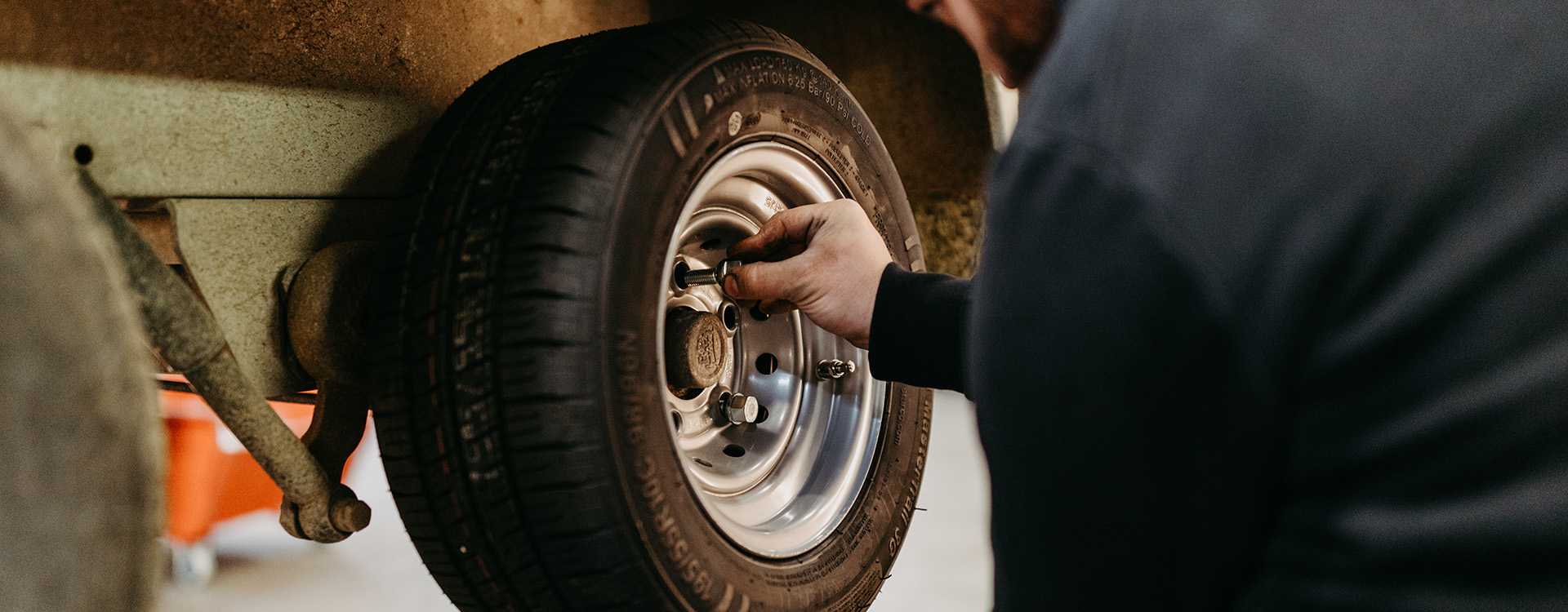 Ein Mechaniker montiert Räder an einem Anhängerfahrgestell in einer Produktionshalle