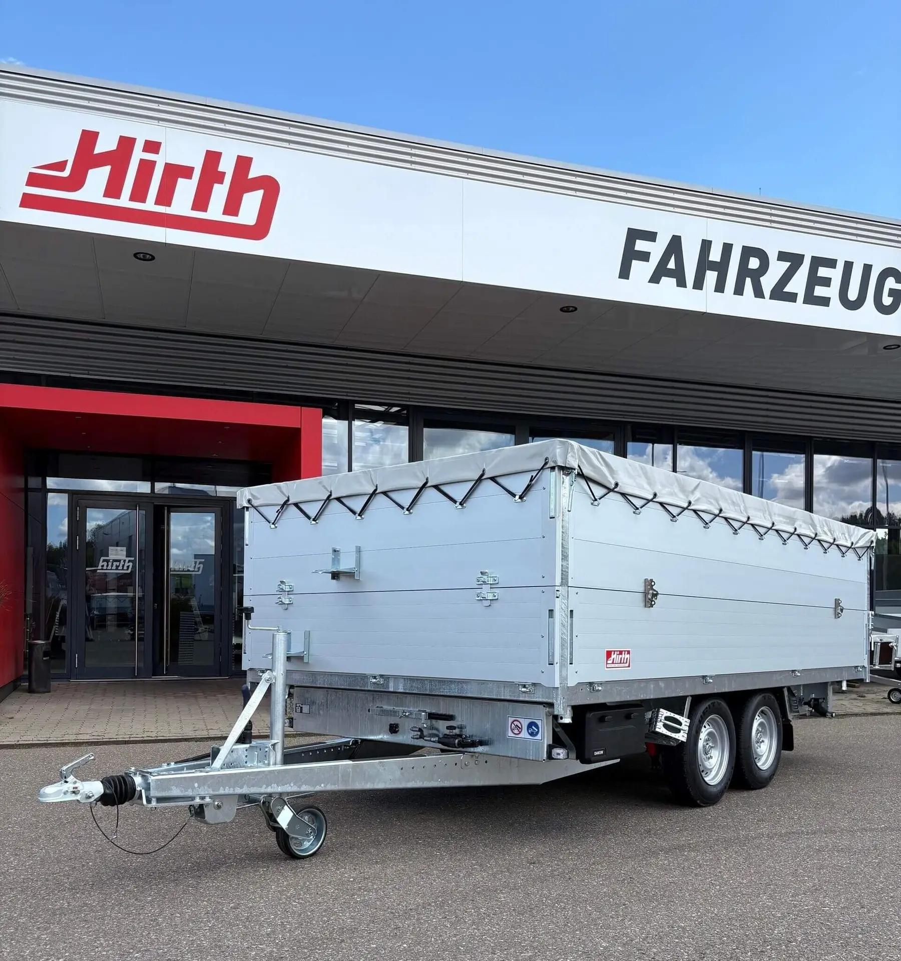 Ein Hirth-Anhänger mit Plane steht vor dem Firmengebäude in Deißlingen